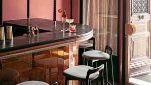 A bar area with stools, a bar counter, and shelves with bottles. - Il Palazzo Experimental (Venice)