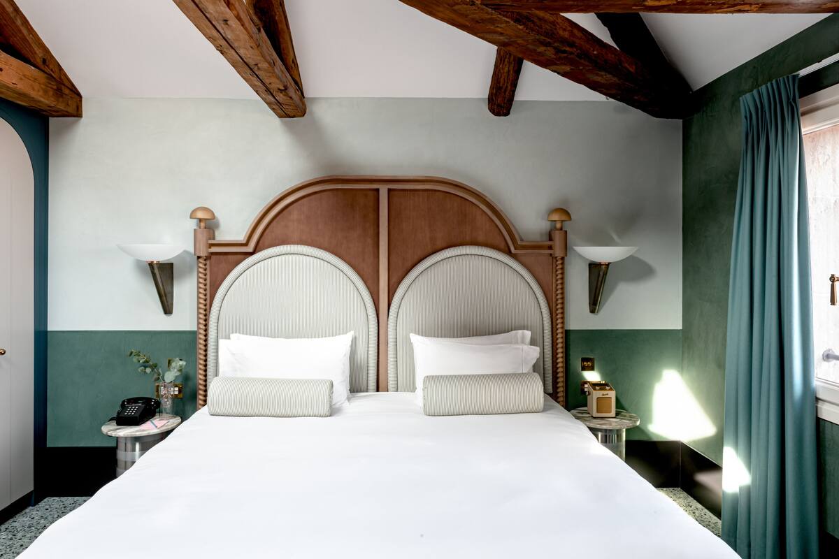 A double bed with a wooden headboard, two bedside tables with lamps, and a nightstand with a telephone.