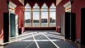 A corridor with large windows, a view of a waterfront, and a patterned floor. - Il Palazzo Experimental (Venice)