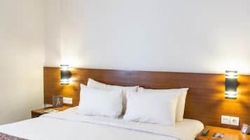 A hotel room with a large bed, wooden headboard, bedside tables, and wall-mounted lights.
