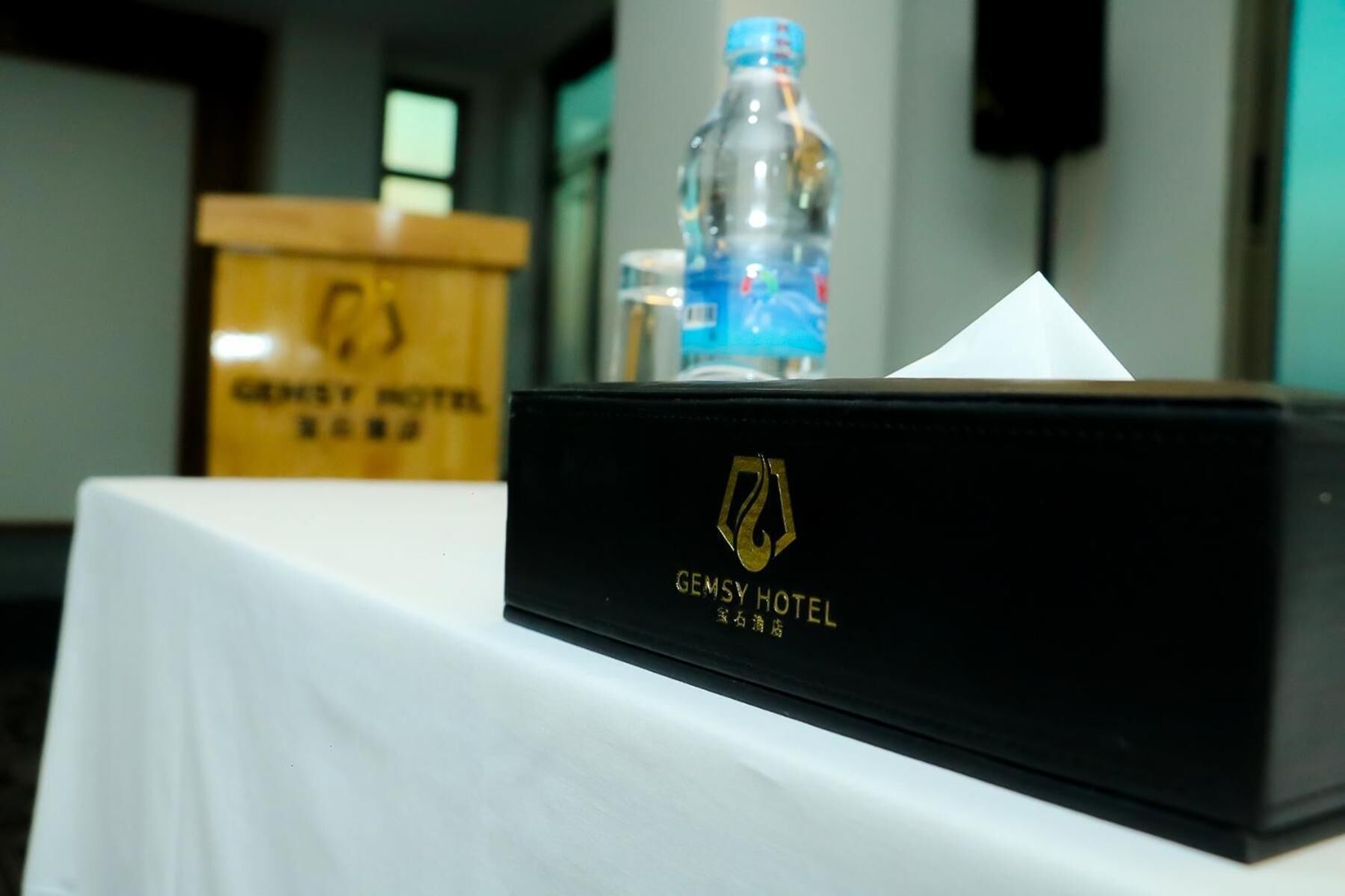 A black box with the GEMSY HOTEL logo on a white tablecloth.