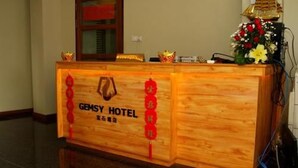Un mostrador de recepción de madera con el texto "GEMSY HOTEL" y detalles decorativos.