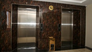 Un elevador moderno con paredes de mármol y un pequeño armario de madera en el centro.