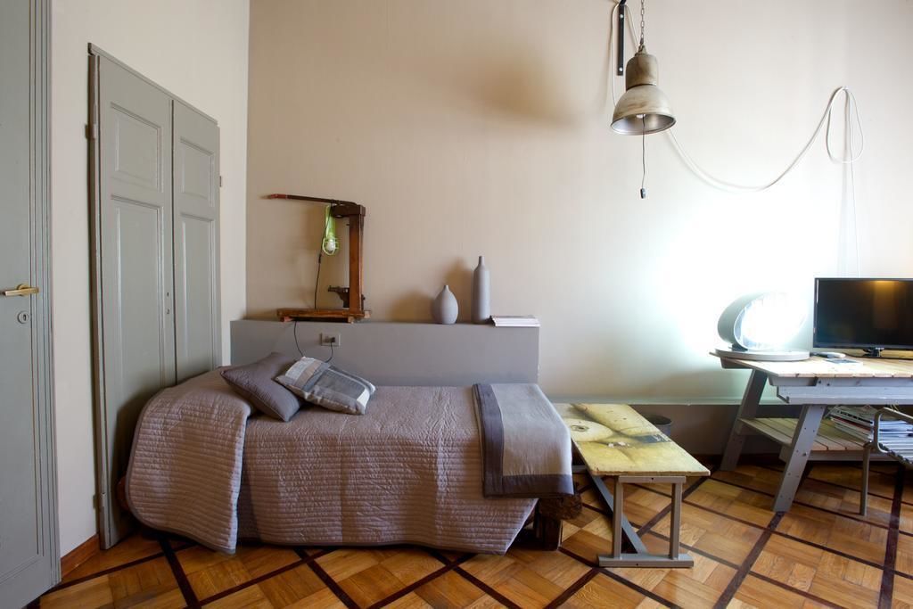 A compact bedroom with a bed, a desk, and a television.
