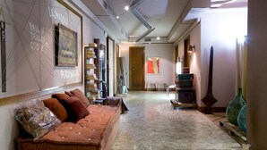 A hotel corridor with a sofa, bookshelves, and artwork. - Bed più Art (Milan)