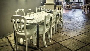 A dining area with a wooden table and white chairs, a tiled floor, and a view of the outdoors through a window. - Bed più Art (Milan)