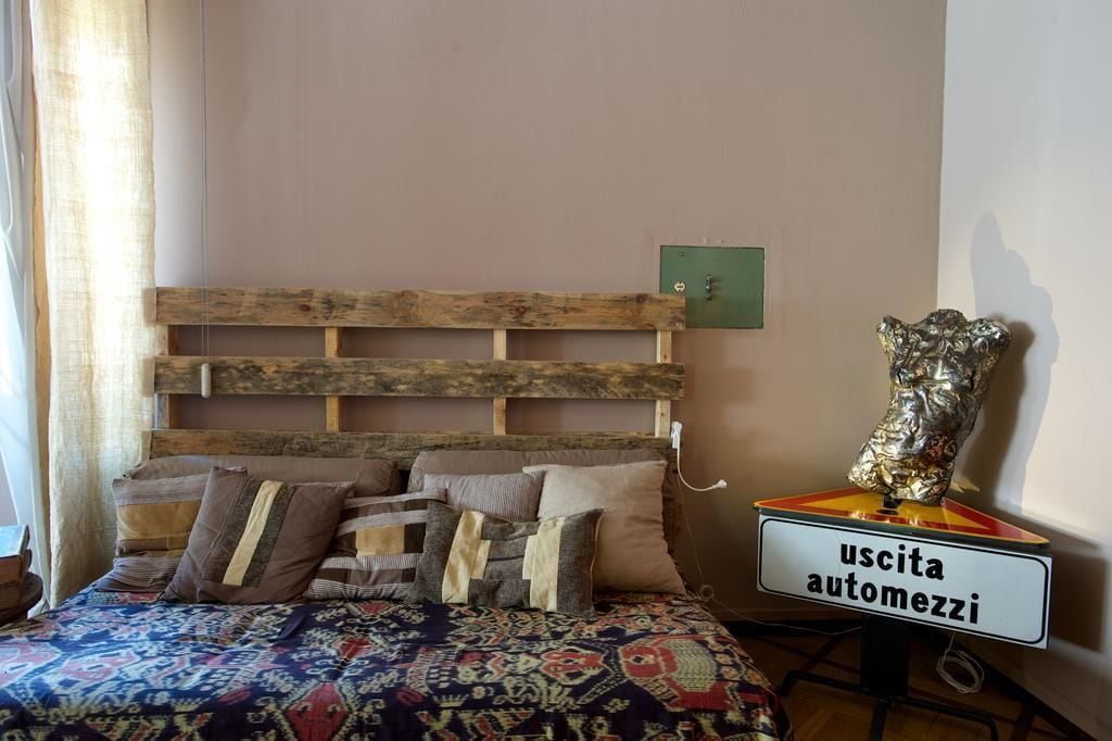 Une chambre à coucher avec une tête de lit en bois, une couvre-lit à motifs et un panneau indiquant la présence d’une salle de bain attenante.