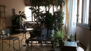 A cozy indoor space with a round table, chairs, and various potted plants. - Bed più Art (Milan)
