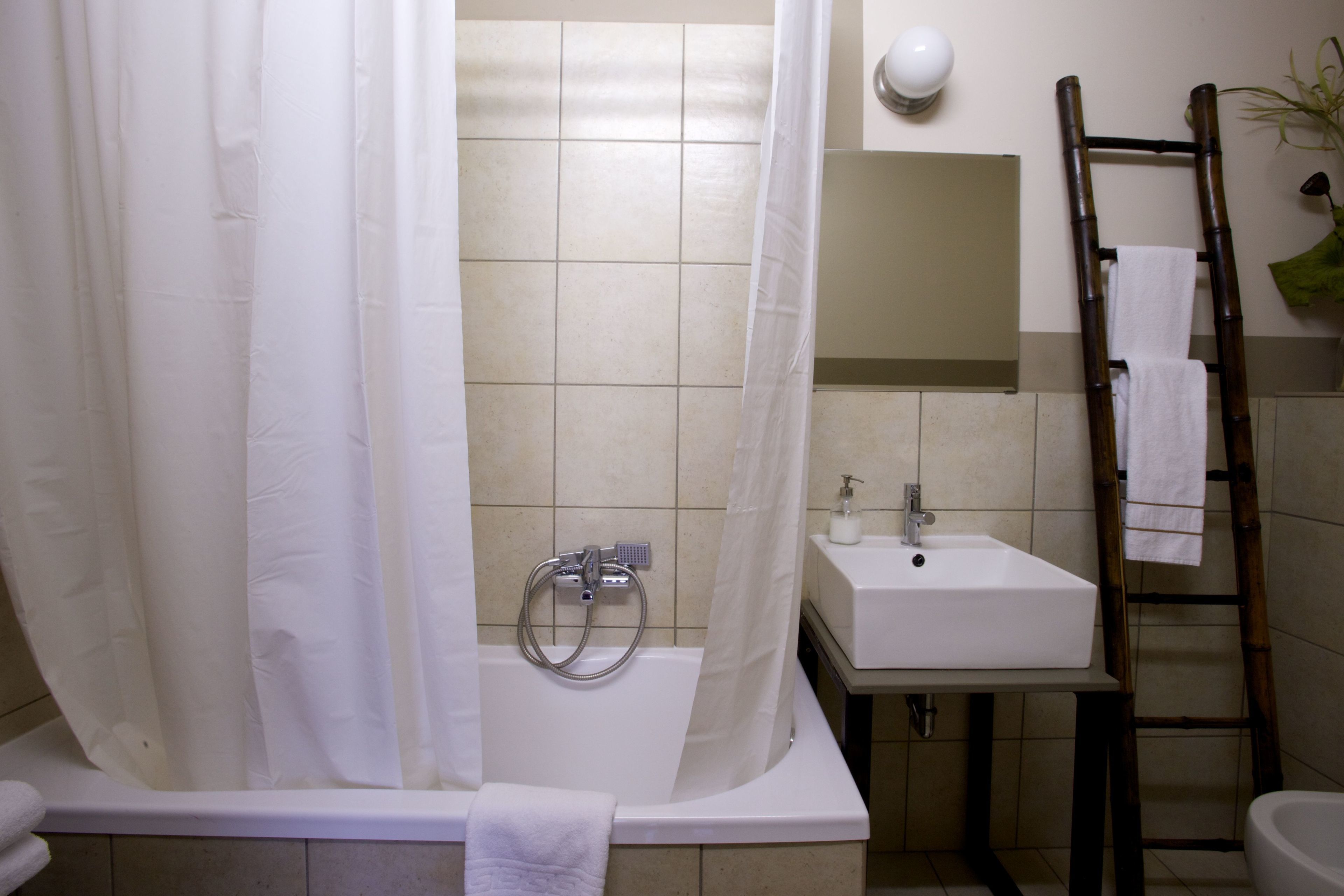A bathroom with a bathtub, a sink, and a shower curtain.
