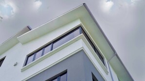 A modern building with a white facade, large windows, and a prominent corner design. - Vulcan Suites (Abuja)