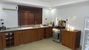 A kitchen with wooden cabinets, a stove, and a sink. - Vulcan Suites (Abuja)