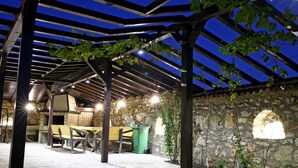 An outdoor covered patio with stone walls, wooden benches, and a pergola structure. - Villa Heaven Hills (Balchik)