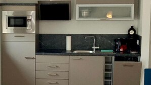 Uma cozinha compacta com micro-ondas, fogão, pia e cafeteira.