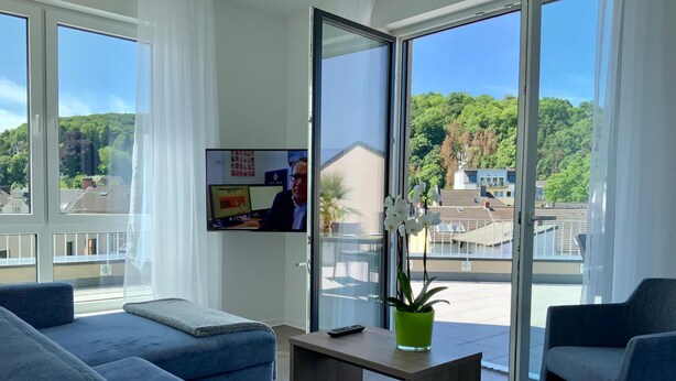 Uma sala de estar moderna com um sofá, uma mesa de centro e uma televisão na parede.
