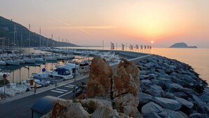 A marina with boats docked, a rocky shoreline, and a sunset in the background. - Bed & Breakfast Alassio (Alassio)
