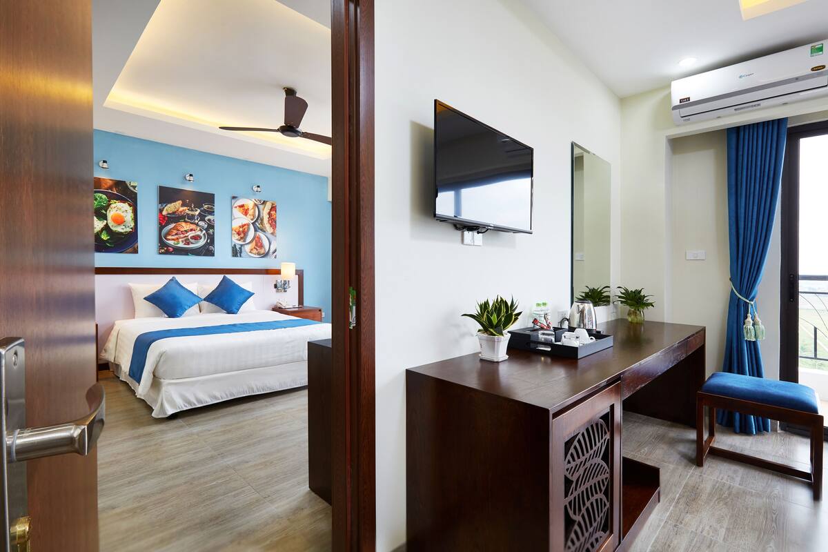A hotel room with a bed, a desk, a TV, and a ceiling fan.