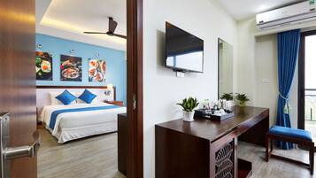 A hotel room with a bed, a desk, a TV, and a ceiling fan.