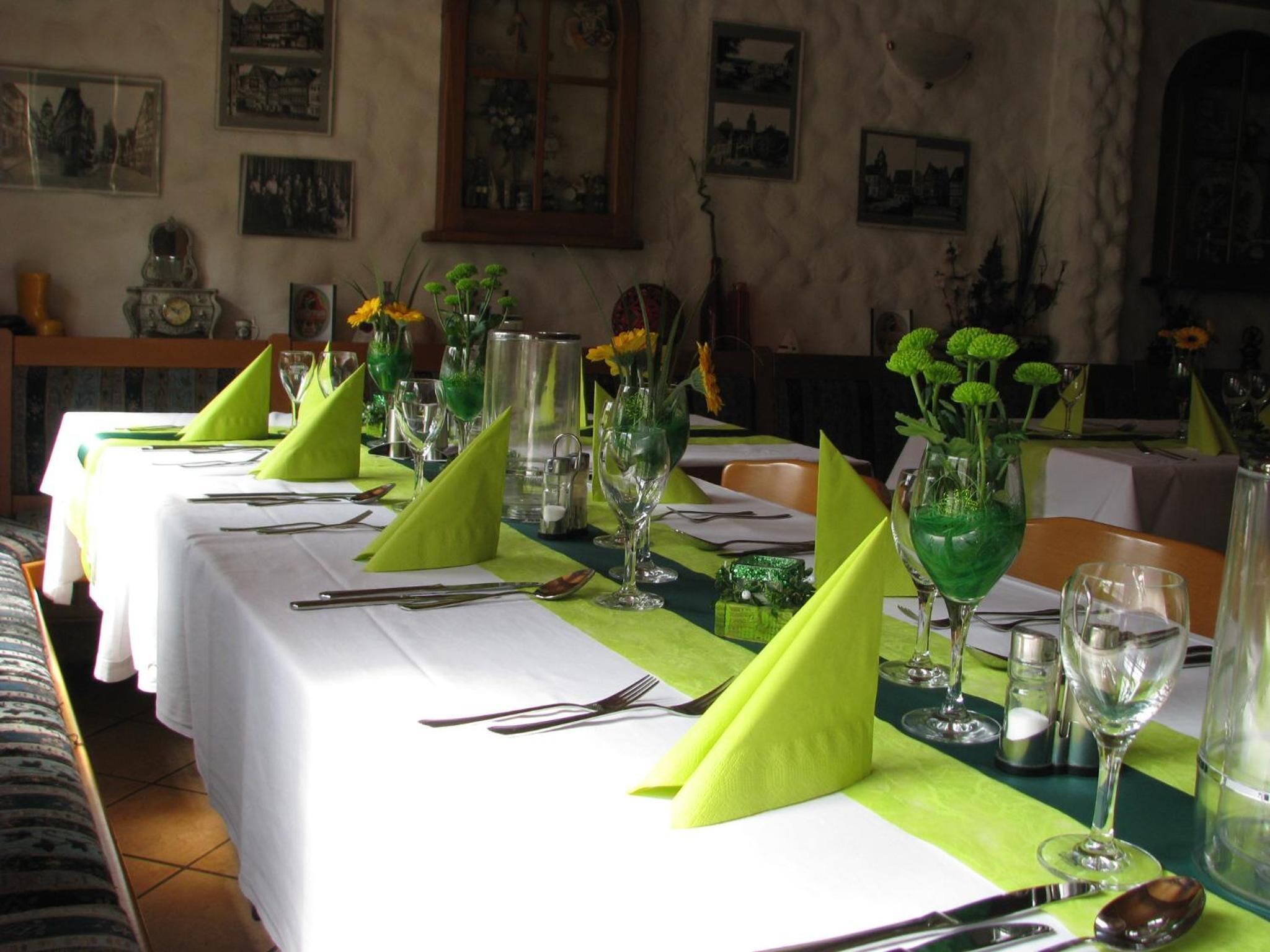 Taula de dinar posta amb serretes verdes, vetrereria transparent i centrals florals.