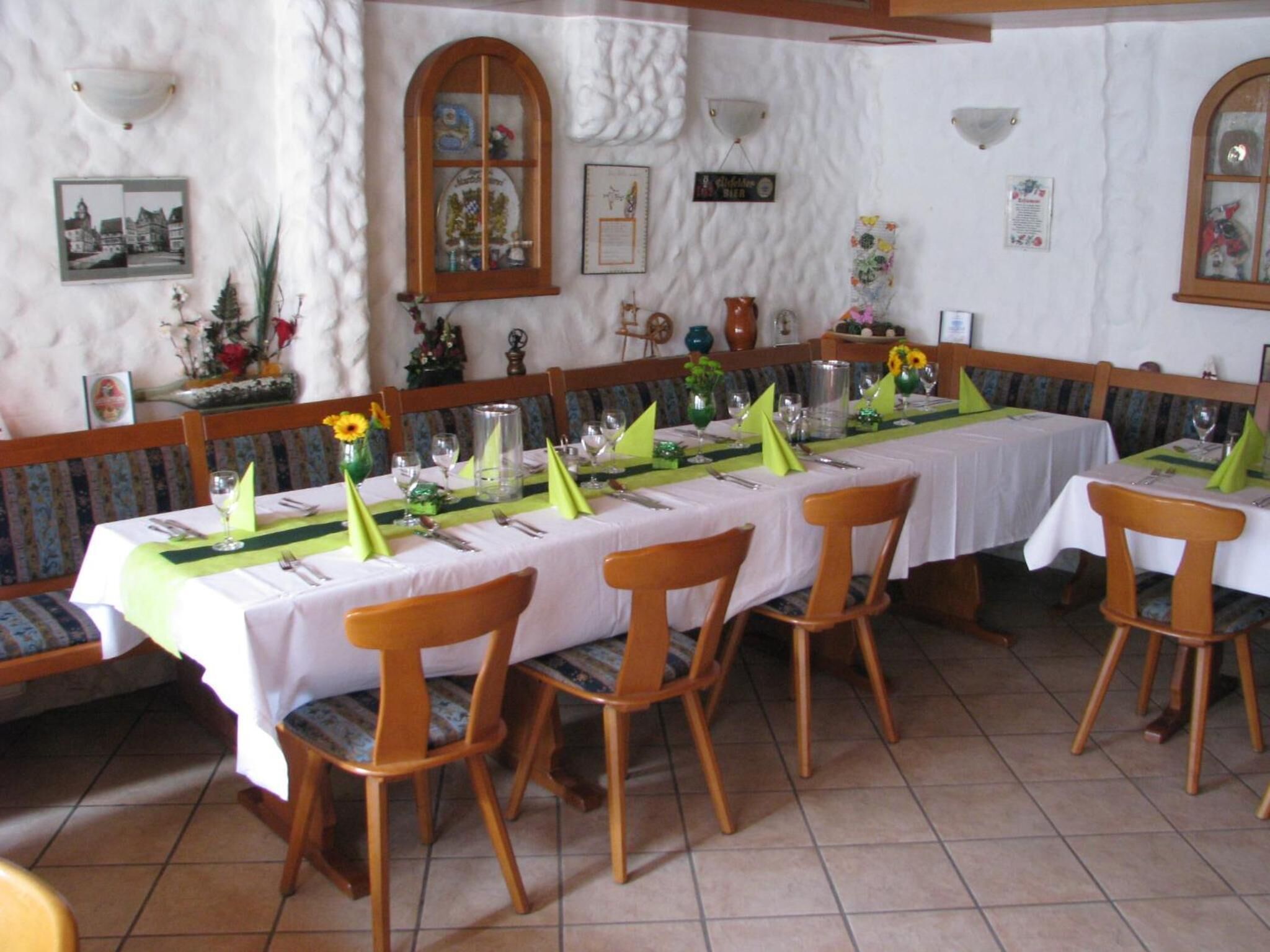 Un espace repas avec des tables disposées pour accueillir quatre personnes, des chaises en bois et un sol carrelé de couleur blanche.