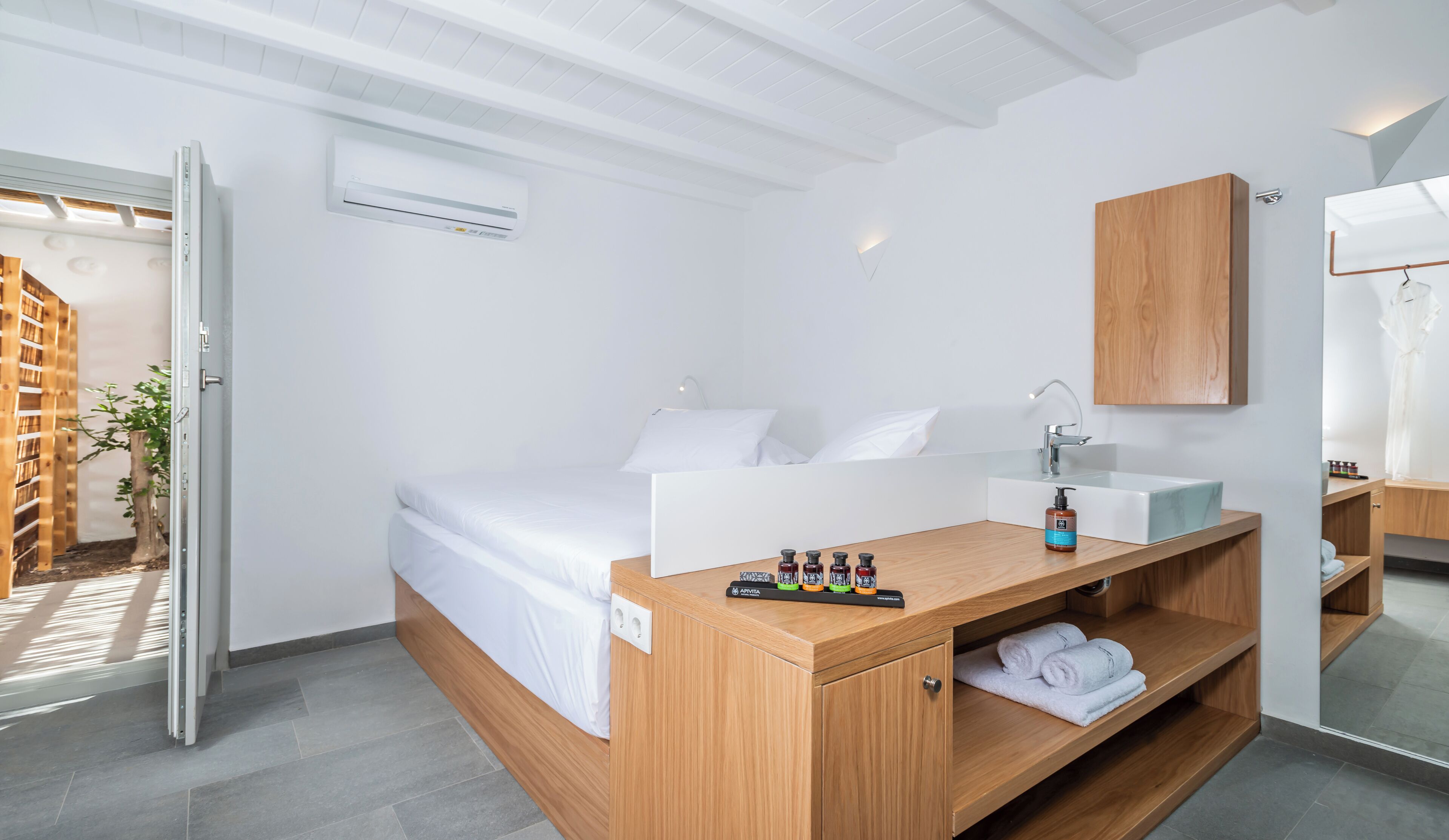 Quarto de hotel moderno com uma cama, uma toucador de madeira, uma pia e um espelho.