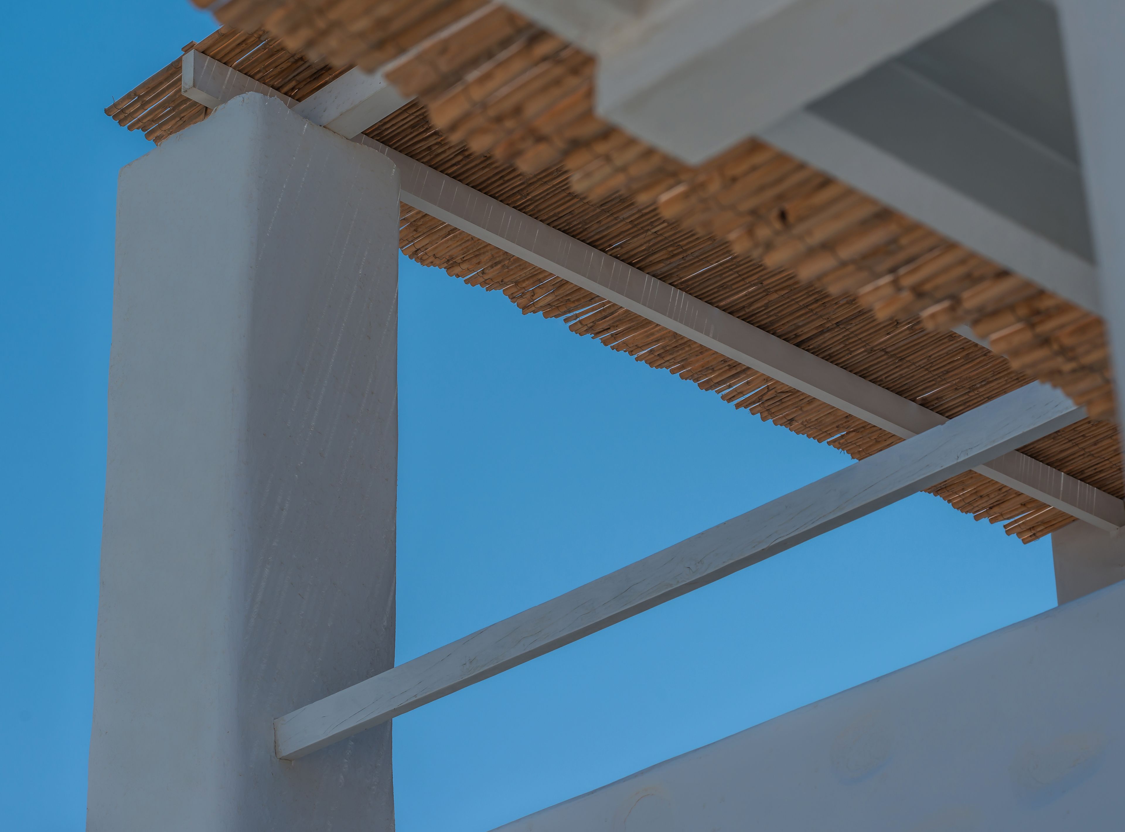 A white structural support with a wooden thatched roof.