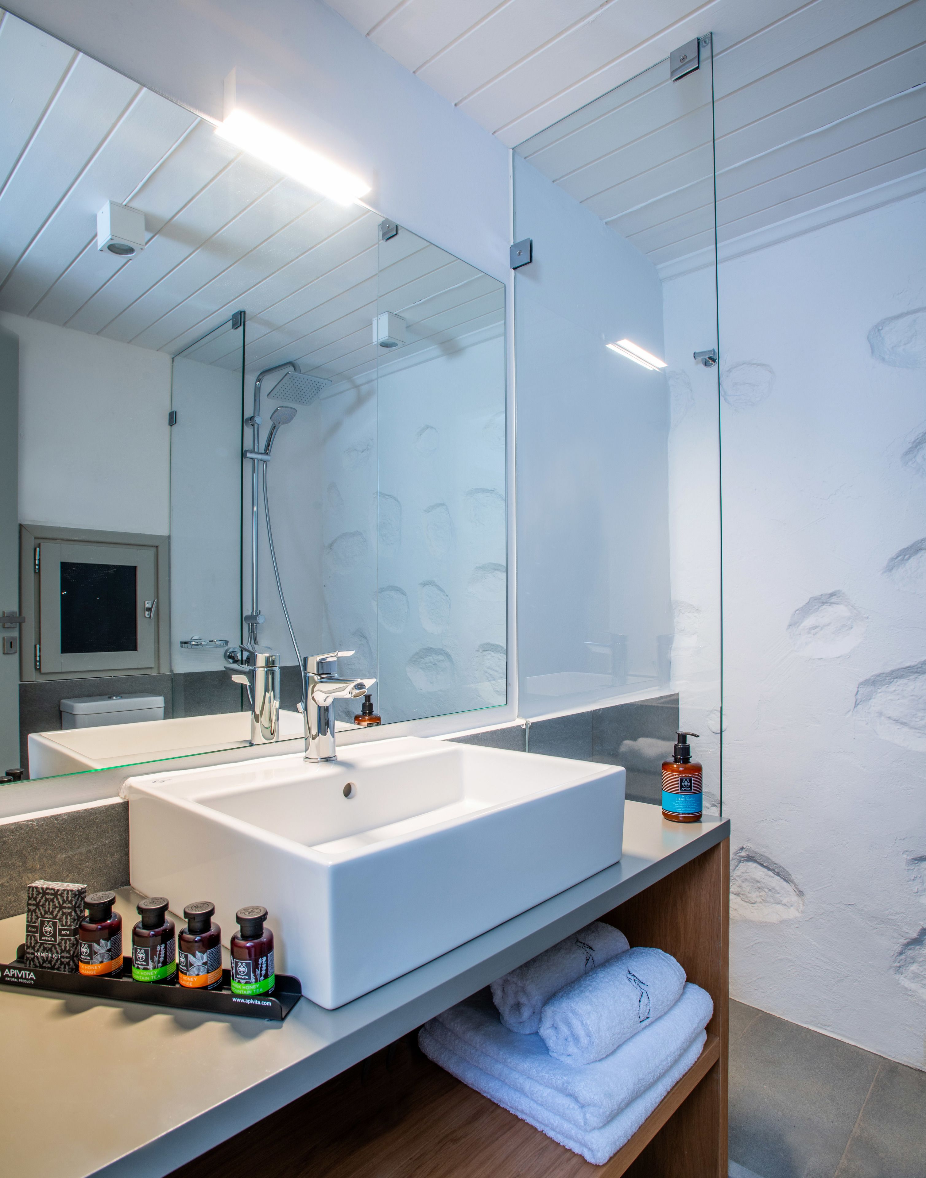 A modern bathroom with a large mirror, a white sink, and a glass shower enclosure.