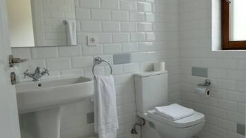 A bathroom with white subway tiles, a sink, a toilet, and a patterned floor.