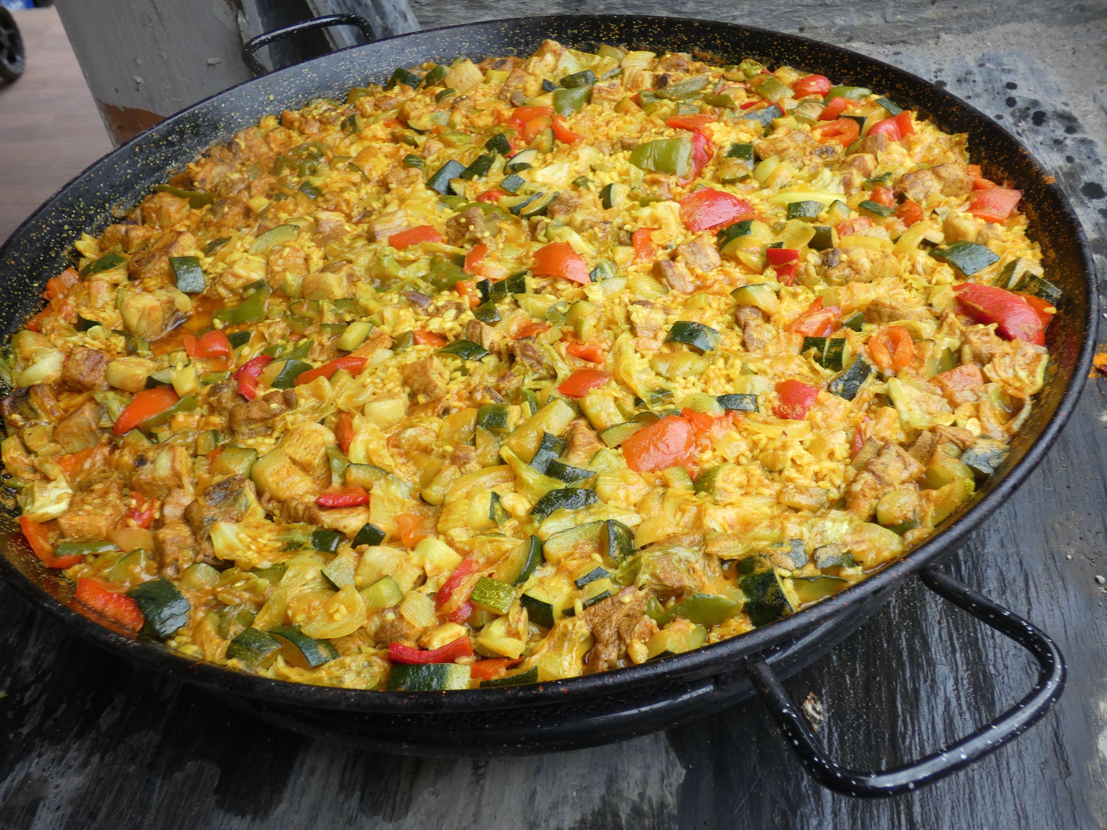 Una sartén negra grande llena de un plato colorido de verduras y carne.