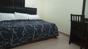 Un dormitorio con cama, mesita de noche y silla.