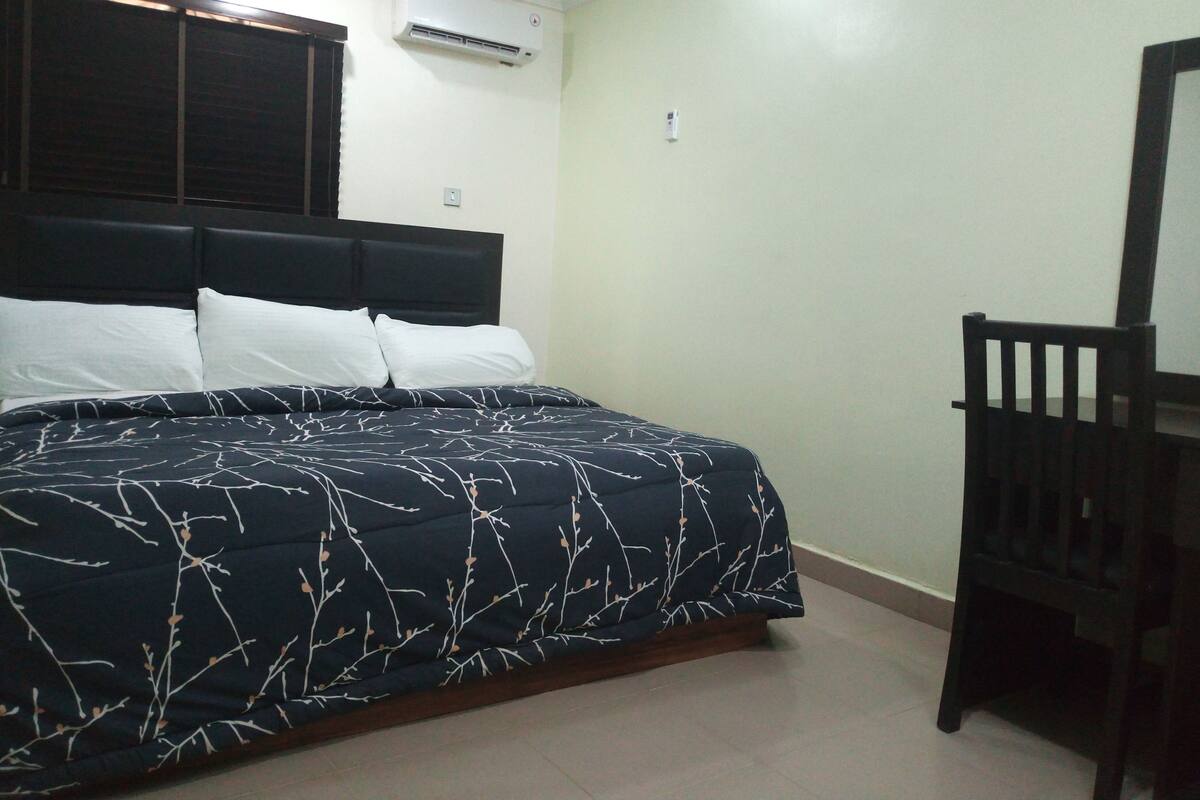 Un dormitorio con cama, mesita de noche y silla.