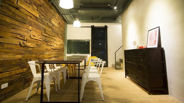 A room with a wooden wall, a table with chairs, a dresser, and a window with a view. - 176 Together Hostel (Hualien City)