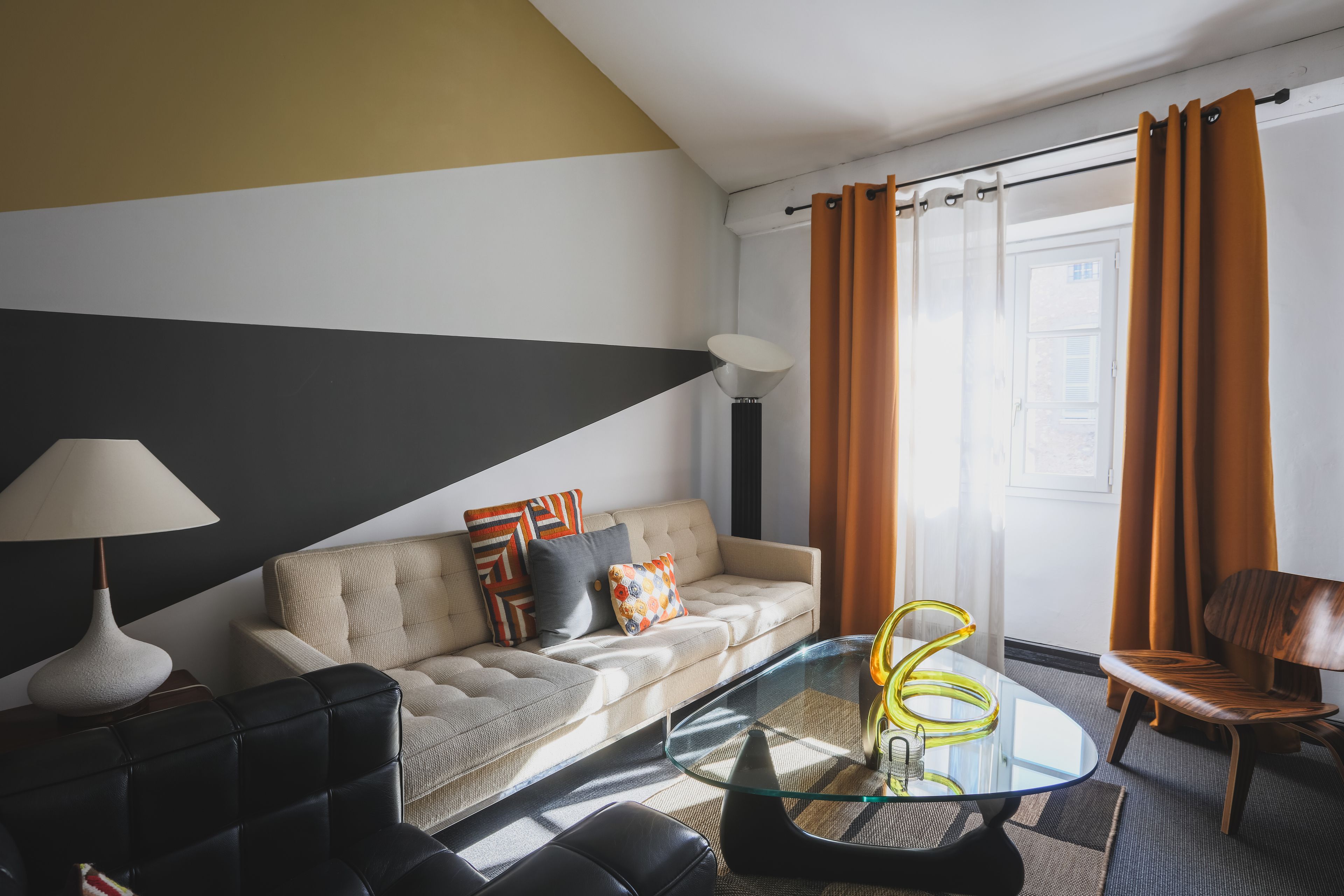 Een moderne woonkamer met een bank, een glazen salontafel, een lamp en een stoel.