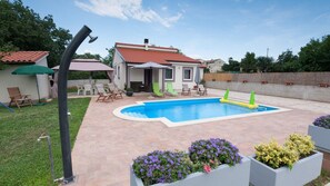 Una piscina al aire libre, sombrillas, sillones reclinables de piscina