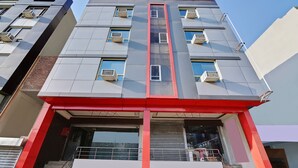 Un edifici modern amb diverses unitats de climatització, una franja vermella central i una entrada de vidre.