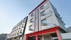 Un edifici de diverses plantes amb un disseny arquitectònic modern, amb un accent vermell destacat a la façana inferior i nombroses unitats de climatització a l'exterior.
