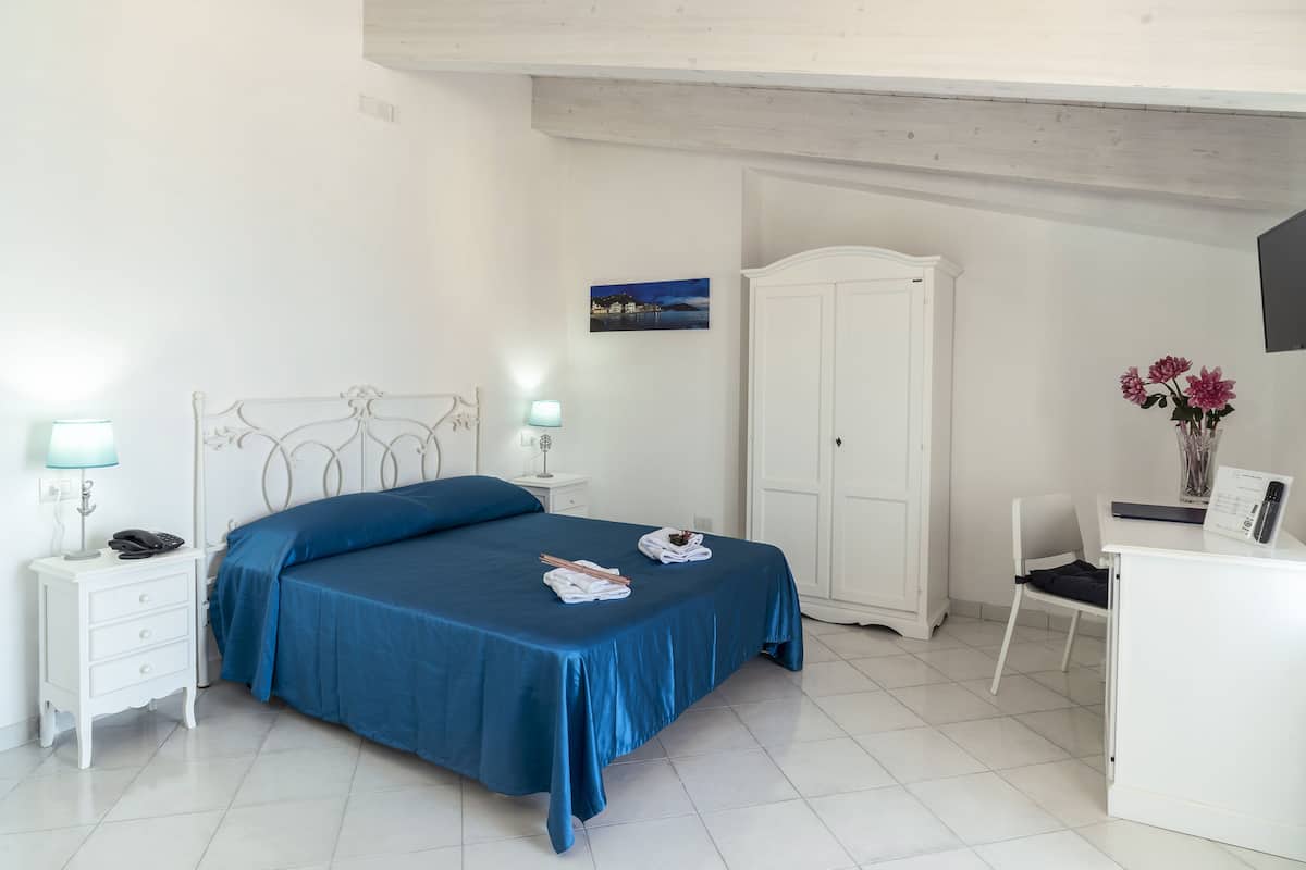 Un dormitorio ordenado con cama, mesitas de noche, armario y escritorio con silla.