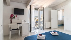 A hotel room with a bed, a desk with a chair, a TV, and a view of the outside. - Residenza d'Epoca Olimpia (Castellabate)