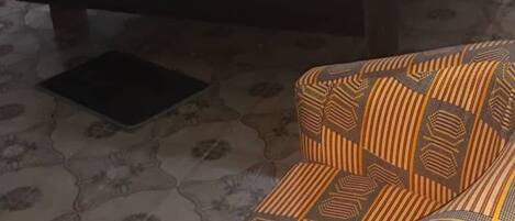 Una habitación con una cama, un sofá estampado y un pequeño tapete negro en el suelo.