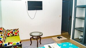A small room with a sofa, a small table, a TV mounted on the wall, and a door leading to another room. - Hotel Restaurant du 3ème Pont (Abidjan)