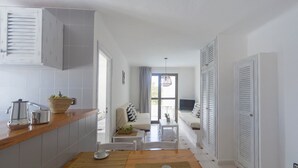 A modern kitchen with a wooden table and chairs, a coffee maker, and a basket of fruit. - Aptos Barbarroja - Formentera Break (Formentera)