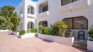 A multi-story building with white exterior walls, multiple balconies, and a tiled patio area. - Aptos Barbarroja - Formentera Break (Formentera)