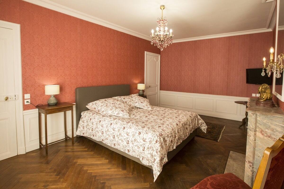 Ein Schlafzimmer mit Bett, einer Kronleuchter, einem Schminktisch und einem Spiegel.