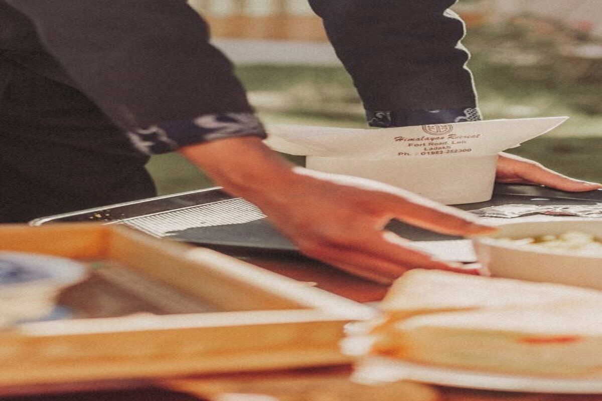 A person serving food from a tray with a paper bag labeled "Himalaya's Finest."
