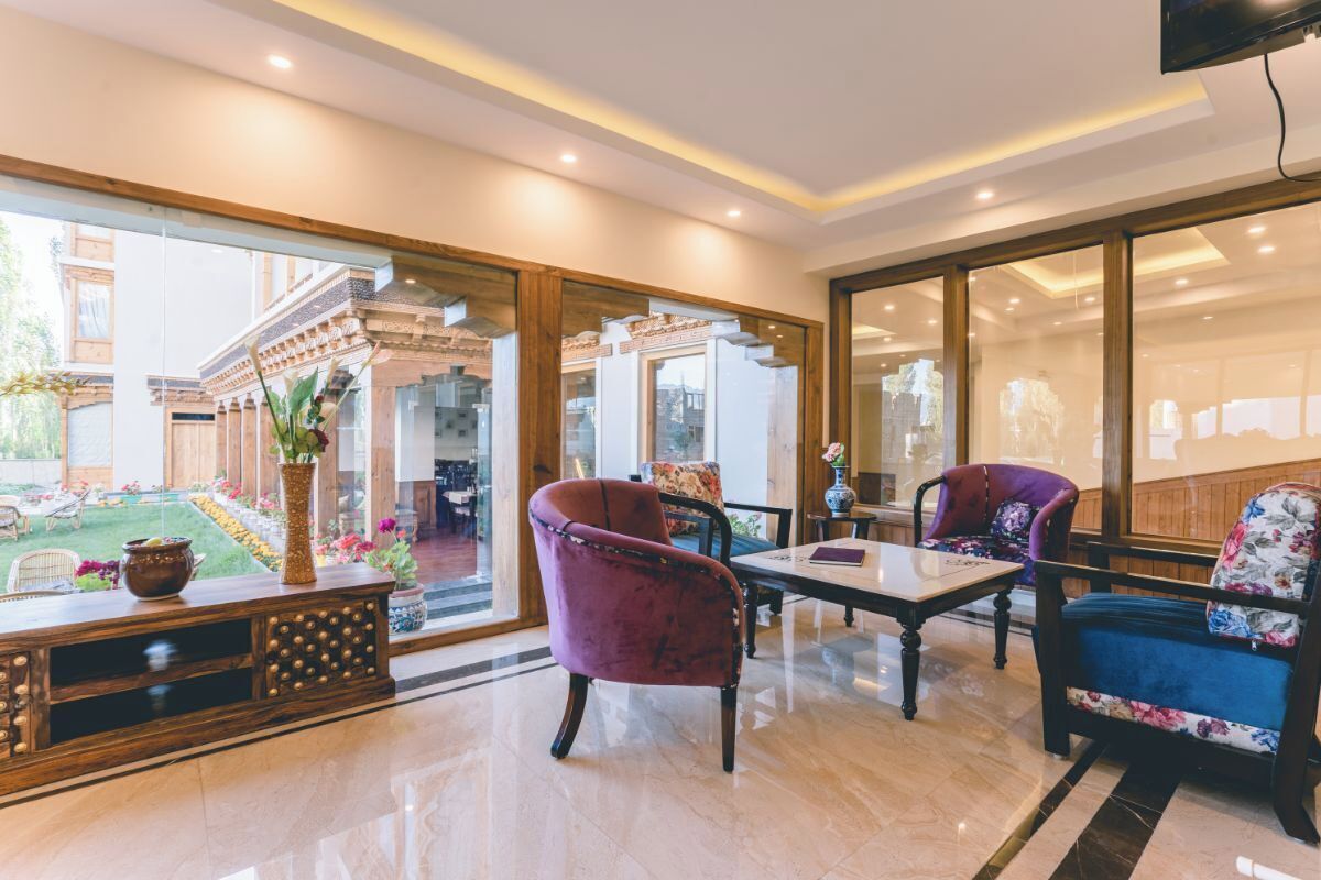 A spacious lobby with a marble floor, a wooden reception desk, and a seating area with purple and blue upholstered chairs.