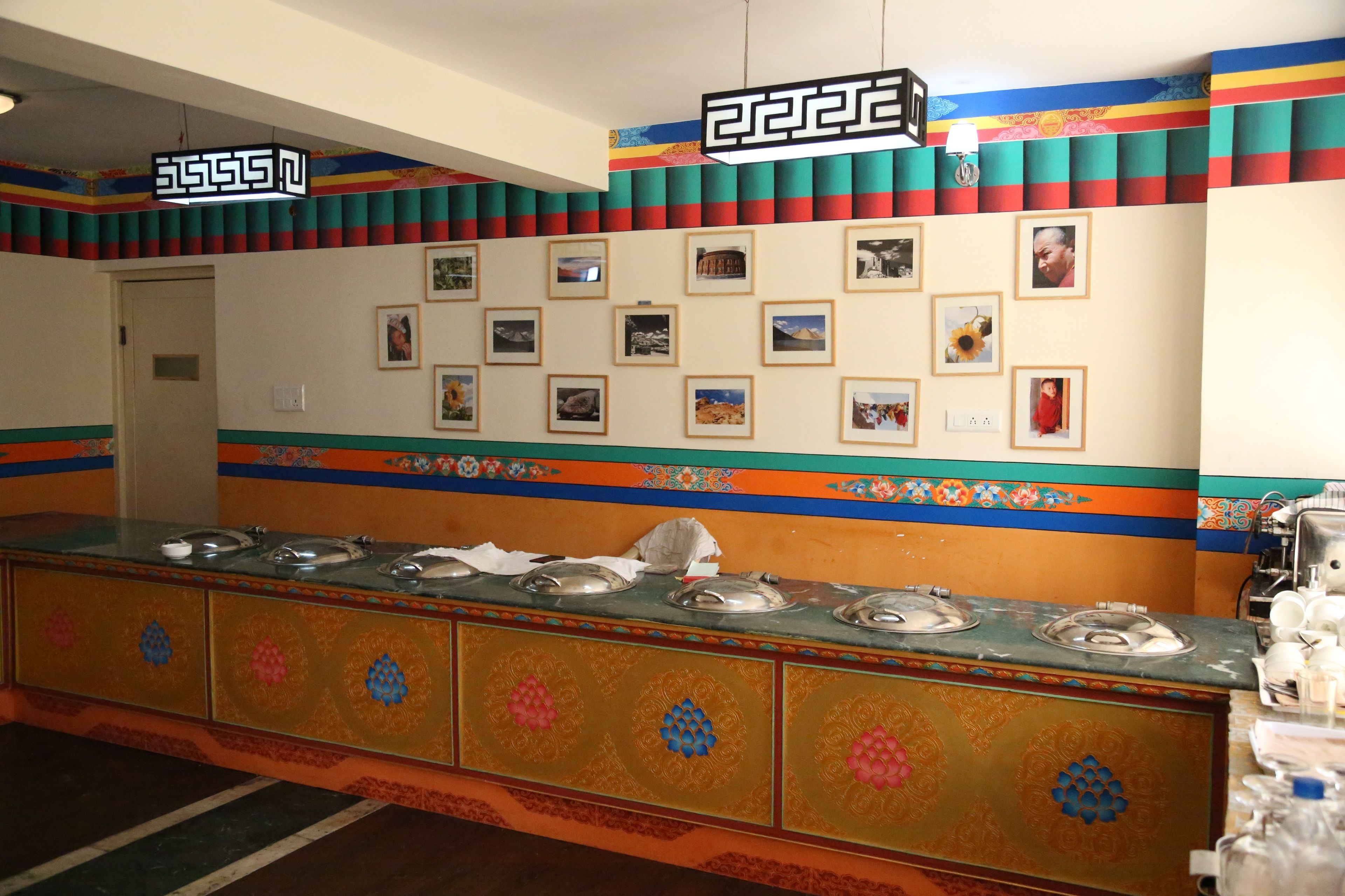 Un área de bufé con una larga mesa de servicio, múltiples estaciones de comida y una pared decorada con fotografías enmarcadas.