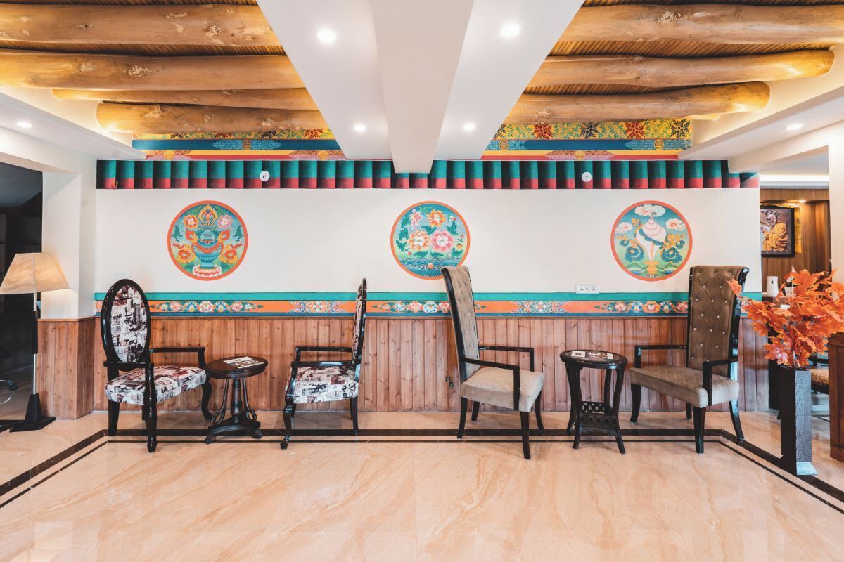 A lobby with wooden ceiling beams, a patterned wall, and a seating area with chairs and a small table.