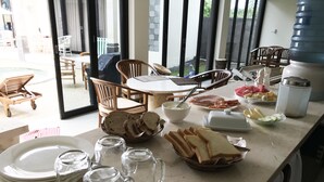 A dining area with a table set for breakfast, including bread, ham, and fruit. - Villa Viking (Jimbaran)