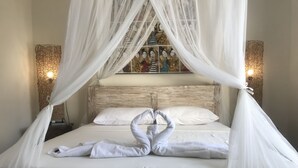 A bed with white linens and a canopy, two bedside lamps, and a wall art piece above the bed. - Villa Viking (Jimbaran)