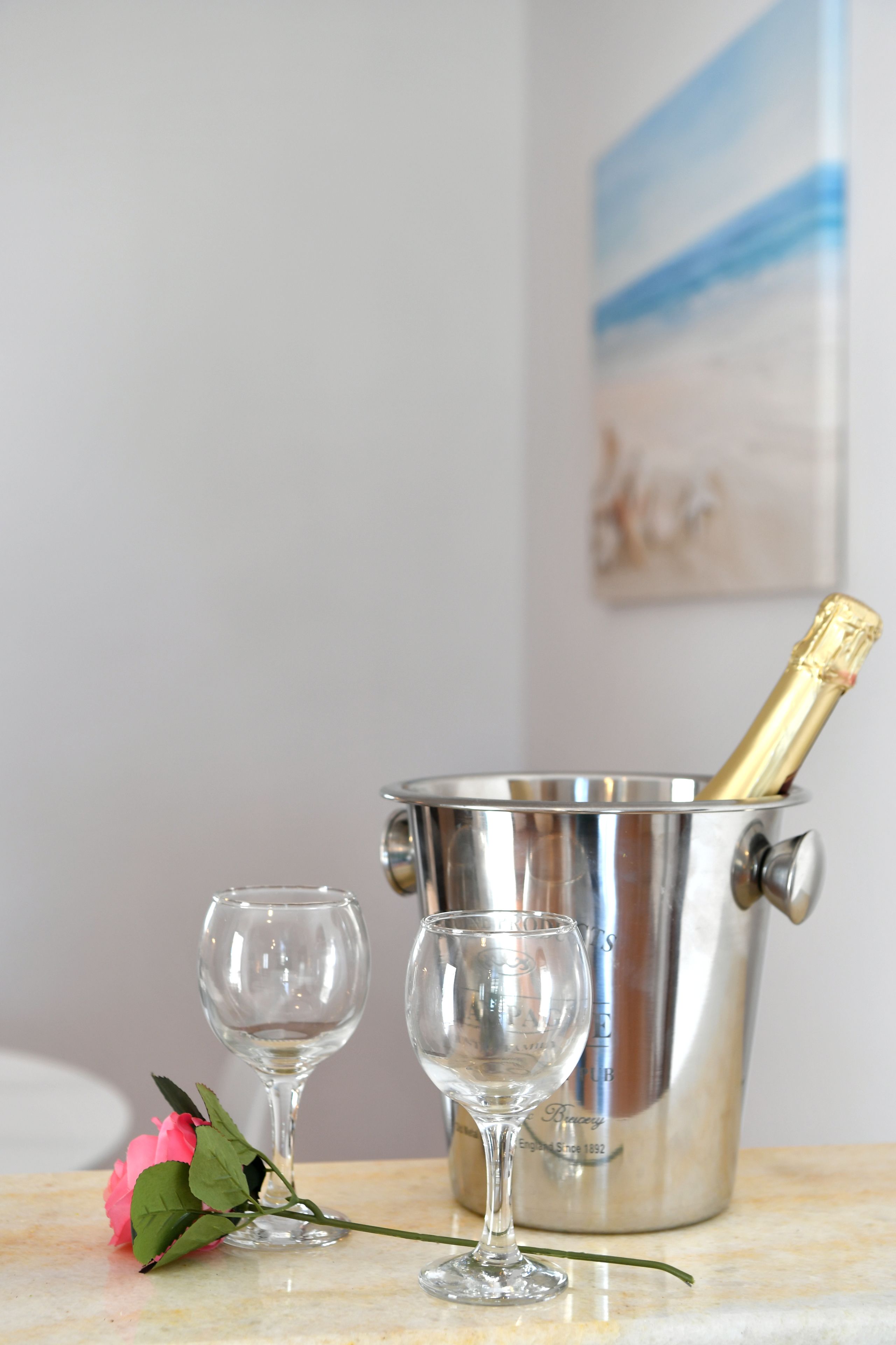 Un seau à champagne avec des verres et une rose posés sur une surface en marbre.