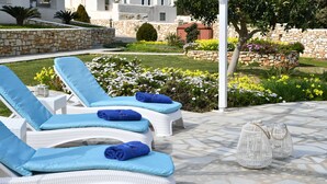 Une terrasse avec des fauteuils de jardin en osier blanc, des coussins bleus et des lanternes blanches.